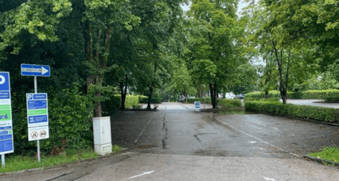 Foto von der Einfahrt auf den Parkplatz des Strandbad Breitbrunn mit Beschilderung über die digitale Parkaufsicht
