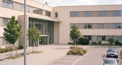 Haltebuchten vor dem Eingang einer Klinik, eine Kamera am Mast erfasst die Zufahrt
